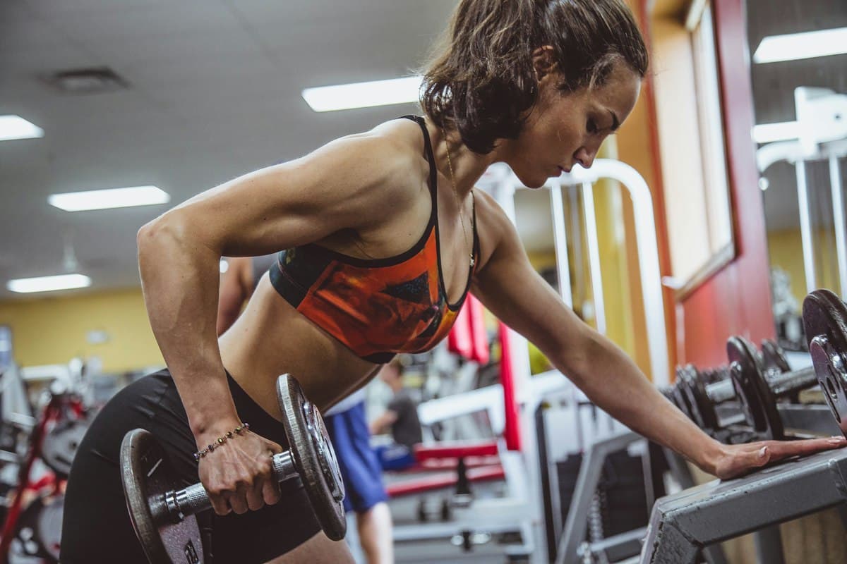 A woman doing a dumbbell row in a gym