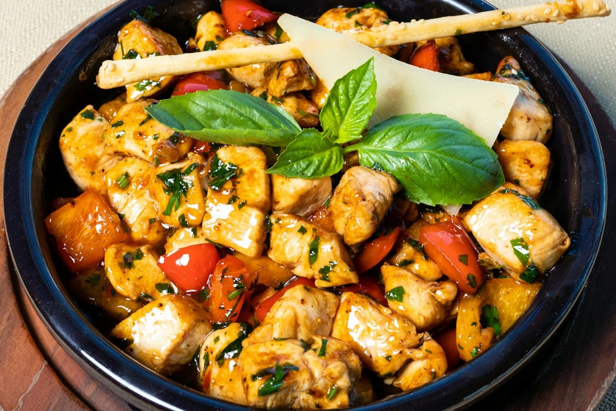 A pan of chicken cooked with tomatoes and fresh basil
